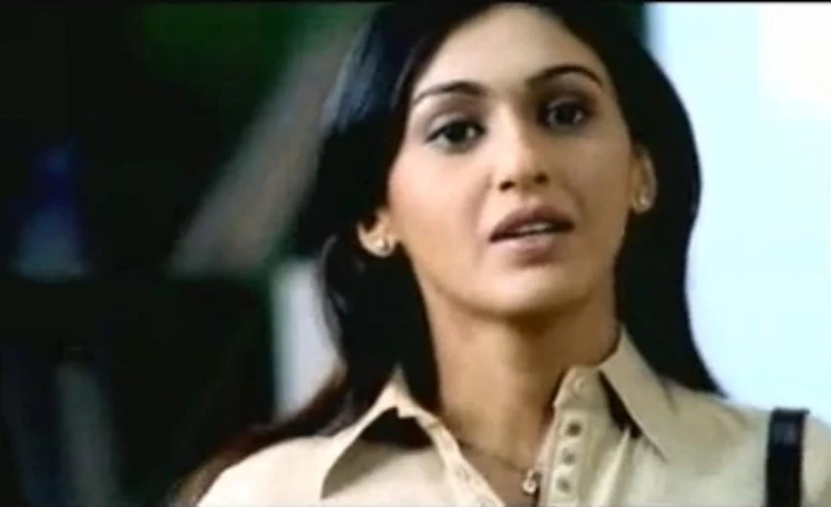 Kuljeet Randhawa looking at something while wearing a beige blouse and necklace